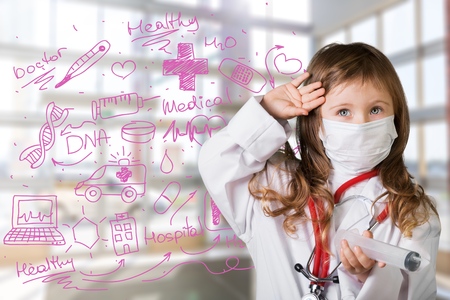Little girl plays doctor examining baby doll patient with toy stethoscopeの写真素材