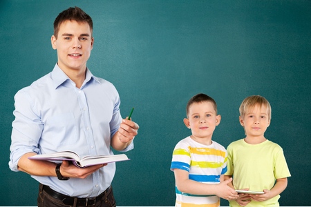 Young teacher near chalkboard in school classroomの写真素材