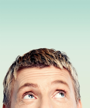Closeup of a man looking upwards smiling on white