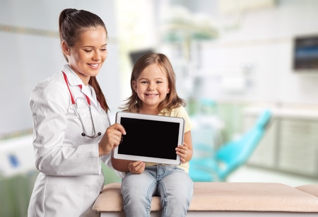 Young woman doctor with little girl  and tablet pcの写真素材