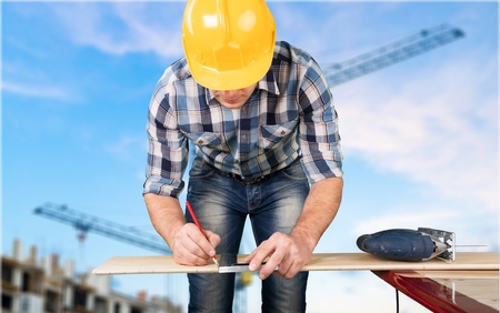 Close up of a carpenter measuring a wooden board.