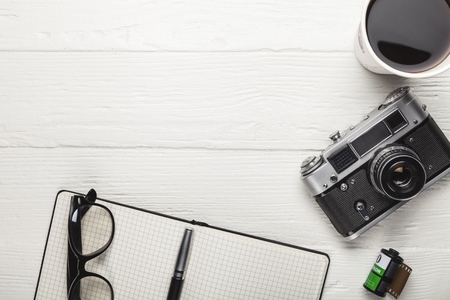Camera, glasses and notepad on wood
