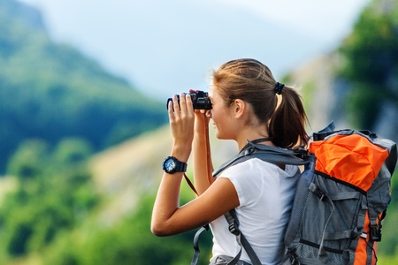 Hiker Looking In Binoculars Enjoying Spectacular View On Mountain Top Above The Cloudsの写真素材