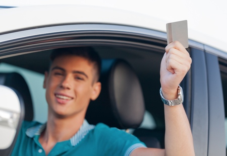 Portrait of Young Man Showing Drivers License in his Carの写真素材