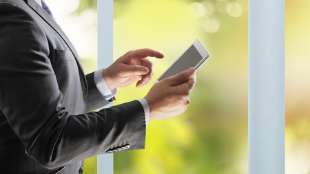 Close up image of business man holding a digital tablet,Portrait of handsome young man working with tablet in the office.Intelligent and confidents businessman holding touch pad with infographicsの写真素材