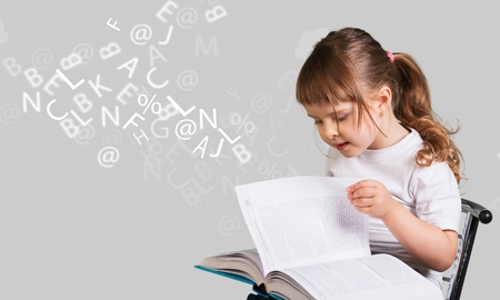 cute little girl with glasses reading a book with departing letters about Chalkboardの写真素材