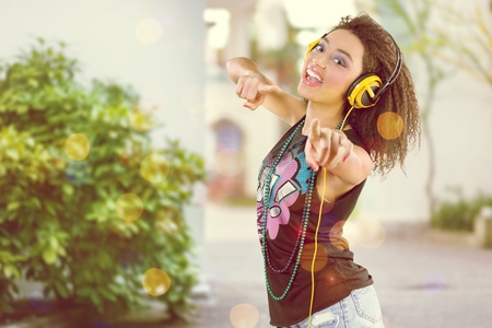 Excited girl dancing and listening music with headphones and smart phone in the street with hair...