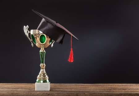 graduation cap with champion golden trophy on wood table with copy space ready for your...