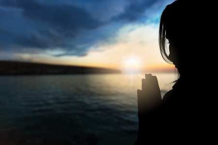 Prayer. Silhouette girl prays at sunset.