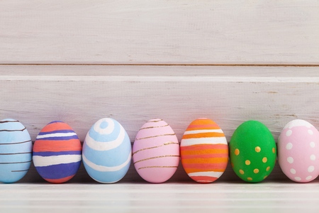 Easter eggs painted in pastel colors on white wooden background. Easter concept