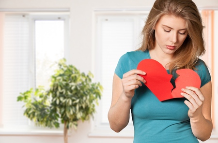Young unhappy girl sitting near the table with broken heart