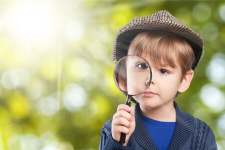 Little boy using magnifier looking close up on white backgroundの写真素材
