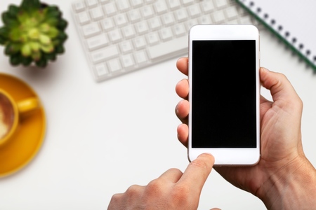 Hand holding smartphone with  application on the screen with laptop background.