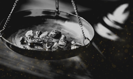 Weighing a gold nugget on a old brass scale dish for trade or exchange.の写真素材
