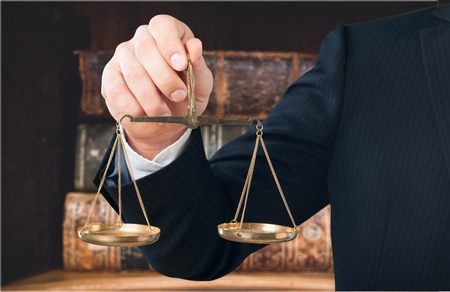 businessman hand holding a balance on white backgroundの写真素材