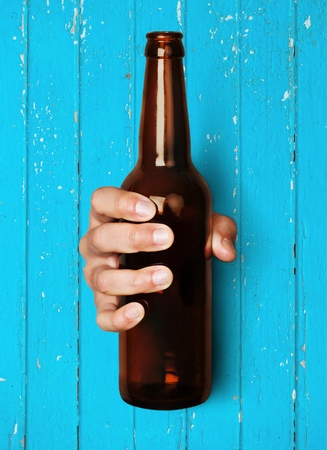 Close-up Of Hand Holding Empty Beer Bottle On White Backgroundの写真素材