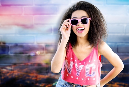 Happy tanned woman with afro haircut enjoying music holding tape recorder.
