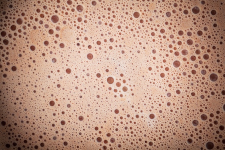 Abstract liquid splash of brown hot coffee on orange background