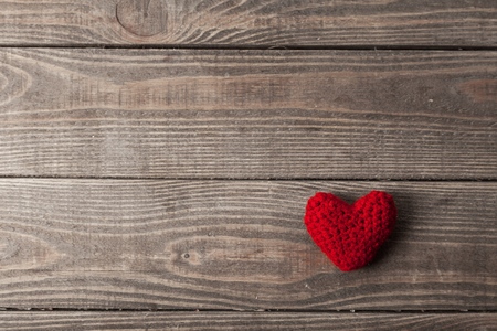 Red paper heart hanging on the clothesline. On old wood background.