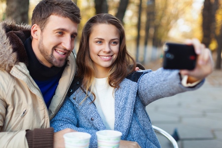 Young woman taking a photo with her mobile phone in a cafe