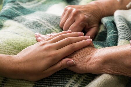 Young Woman's Hand Touching and Holding an Old Woman's Handの写真素材