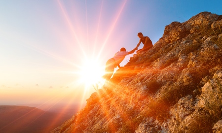 People helping each other hike on the mountainの写真素材