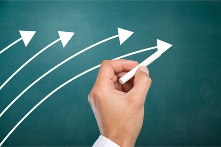 Hand drawing orange arrow as trend leader with many white arrows as follower