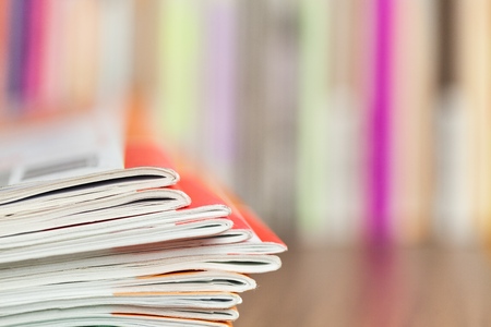 Close up edge of colorful magazine stacking with  blurry bookshelf background for publication and publishing concept , extremely DOFの写真素材