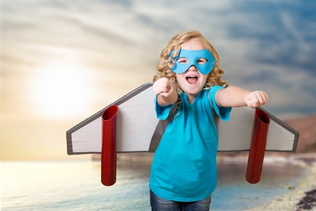 Happy child playing with toy wings against summer sky background. Retro tonedの写真素材