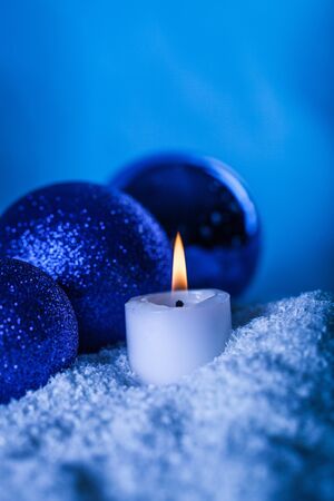 Blue Christmas Baubles and Candle with the Fake Snow on the Blue Backgroundの写真素材