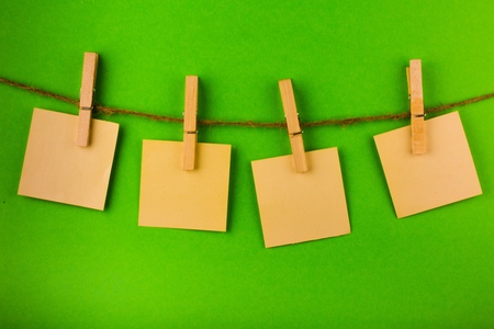 Four Sticky Notes Hanging on Twine Attached with Clothespins on Grey Background