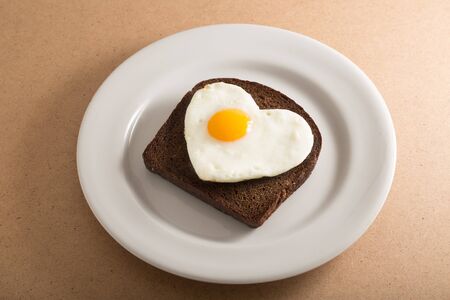Slice of Bread with Fried Egg in the Shape of Heart on the Plate