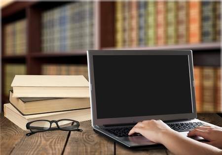 Laptop with books in libraryの写真素材
