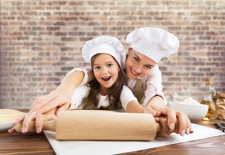 Little girl and her mother cooking at kitchenの写真素材