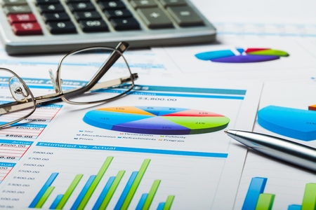 Pen, Calculator and Eyeglasses on Business Graphs and Charts