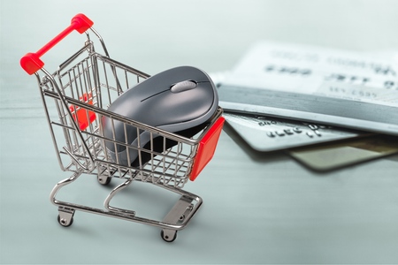 Miniature figurine : a shopper pushes a shopping cart on a smart credit card and a keyboard. Concept of brick and mortar stores nowadays face with increased competition from internet online ecommerce.の写真素材