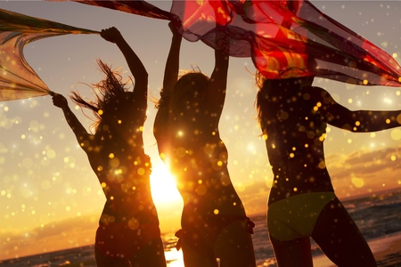 group of happy young people dancing on beachの写真素材