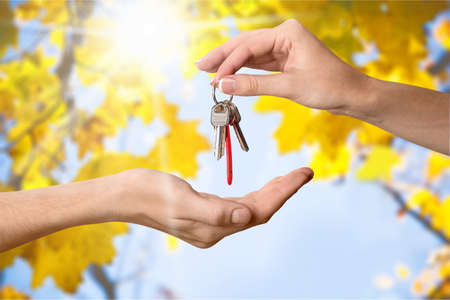 Hand holding three keys over the hand on sunset background, Building concept