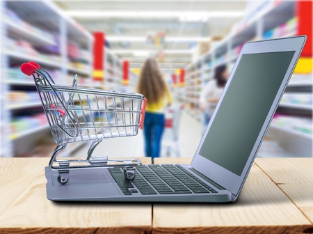 shopping-cart over a laptop isolated on white with reflection