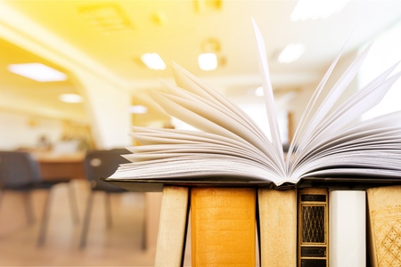 Open book on wood desk in the library room with blurred focus for background, education conceptの写真素材