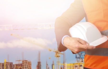building, construction, protective gear and people concept - close up of builder hand holding yellow...