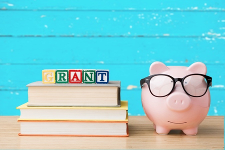 Piggy bank with books on blackboardの写真素材