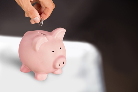 Hand Putting a Coin in Piggy Bankの写真素材