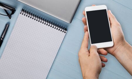 Hand holding phone on workplace background
