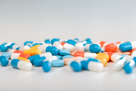 Pharmacy theme. Multicolored Isolated Pills and Capsules on the White Surface. Closeup.の写真素材