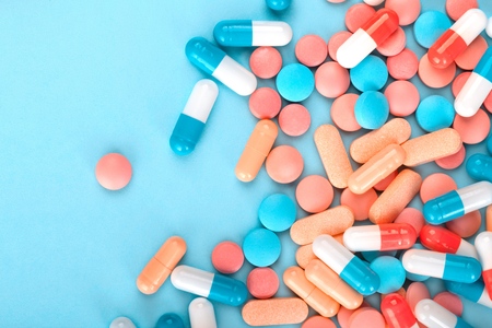 Pharmacy theme. Multicolored Isolated Pills and Capsules on the White Surface. Closeup.