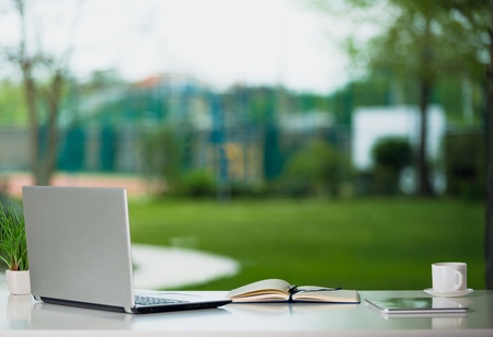 Workplace with notebook laptop Comfortable work table in office windows and city view.の写真素材
