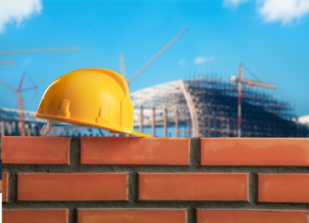 Bricklayer worker installing brick masonry on exterior wall with trowel putty knifeの写真素材