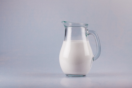 Glass jug of fresh milk isolated on whiteの写真素材