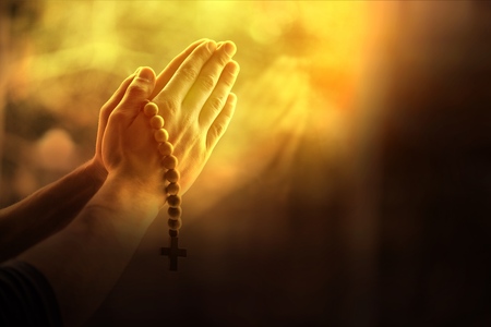Silhouette rosary against cross in hand. Background sunriseの写真素材